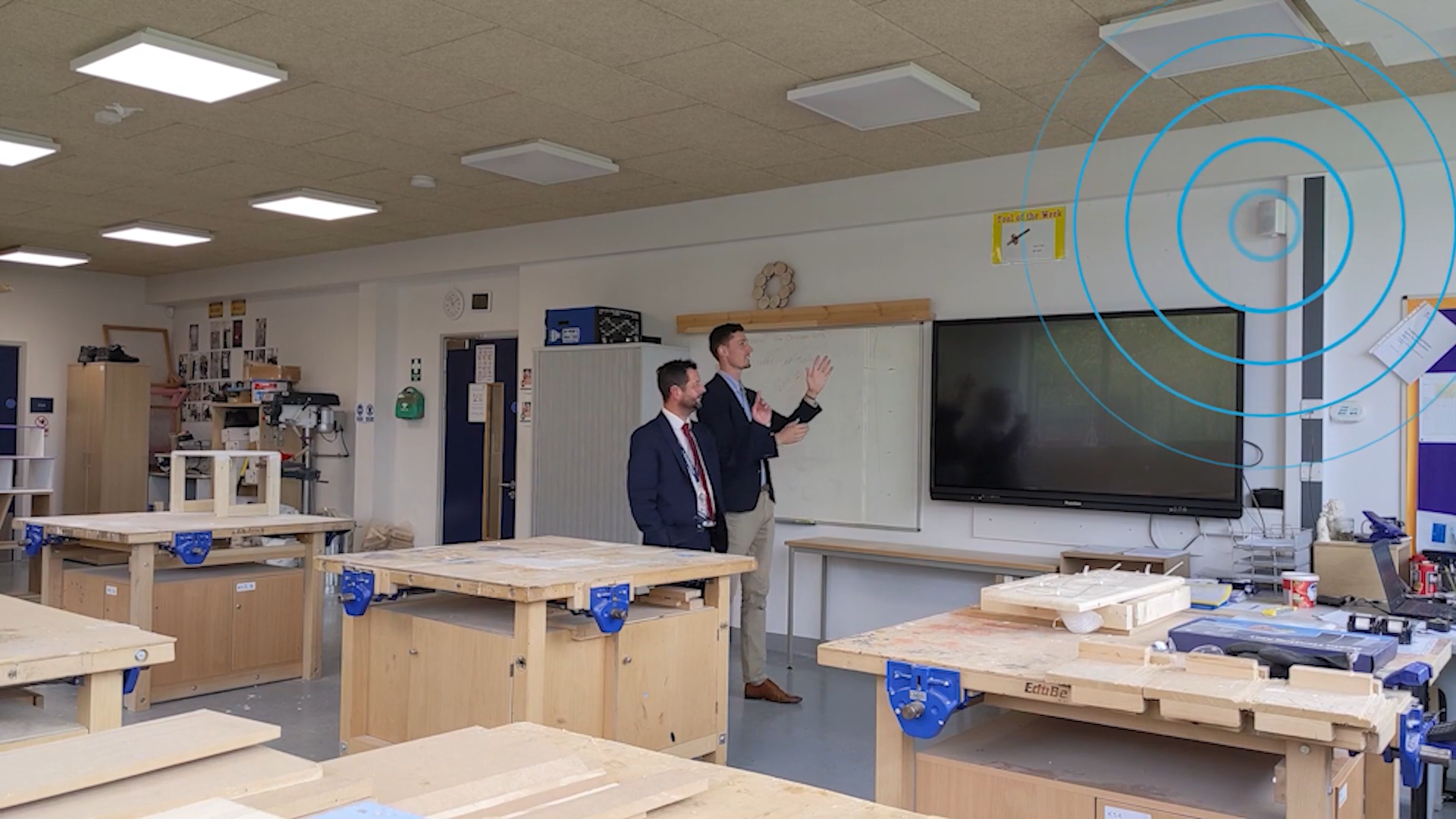 David Bury and Oscar Rowley in a construction workshop at The Heights School, pointing at a speaker installed to address high noise levels.