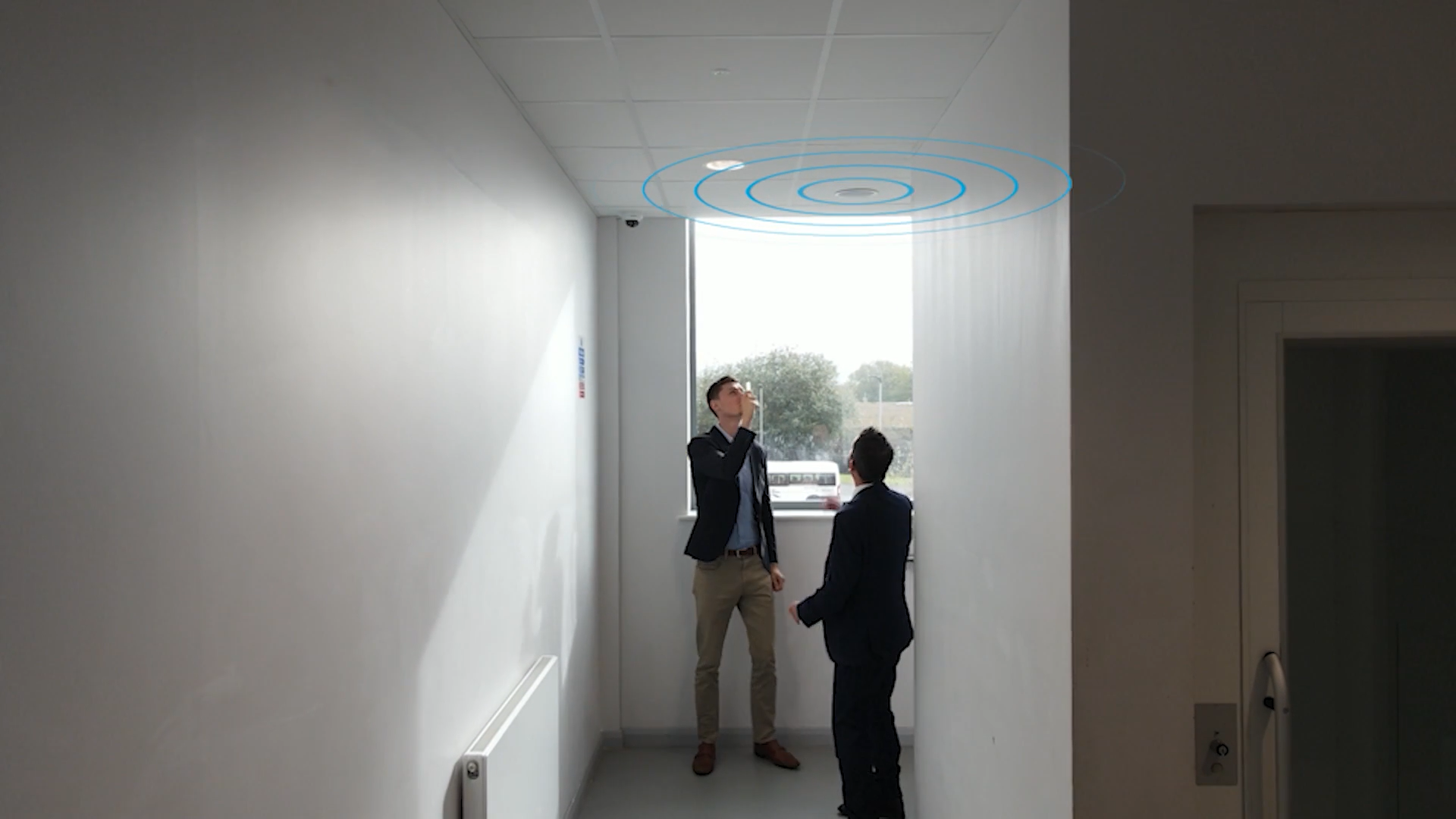 David Bury and Oscar Rowley observing a ceiling speaker at the top of a staircase in The Heights School, covering both the corridor and stairway.